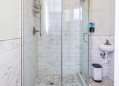 Thumbnail 9 of 12 - A white tiled bathroom with a walk in shower.