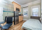 Thumbnail 7 of 12 - A bedroom with a bed, chair, and a kitchenette.
