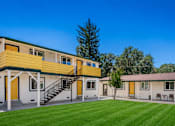 Thumbnail 3 of 16 - A yellow and white building with a green lawn in front.