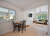 Thumbnail 2 of 16 - A dining room with a table set for two and a couch in the background.