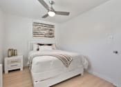 Thumbnail 11 of 16 - A white bedroom with a large bed and a ceiling fan.