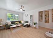 Thumbnail 5 of 16 - A living room with a green couch and a wooden floor.