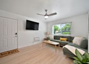 Thumbnail 6 of 16 - A living room with a couch, a coffee table, and a flat screen TV mounted on the wall.