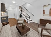 Thumbnail 2 of 20 - A living room with a brown sofa, a coffee table, and a staircase.