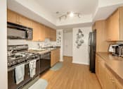 Thumbnail 5 of 32 - A kitchen with wooden cabinets and a black refrigerator.