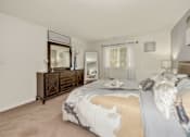 Thumbnail 12 of 32 - A bedroom with a bed, nightstand, and dresser.