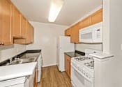 Thumbnail 15 of 32 - A kitchen with white appliances and wooden cabinets.