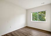 Thumbnail 16 of 32 - A room with a window and wooden flooring.