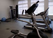 Thumbnail 19 of 22 - A gym with a treadmill, a stationary bike and a rowing machine.