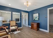 Thumbnail 22 of 42 - A room with blue walls and wooden floors has a chair, a table, and a painting on the wall.