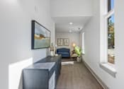 Thumbnail 31 of 42 - A long hallway with a blue couch and a painting on the wall.