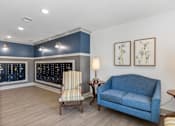 Thumbnail 28 of 42 - A blue couch sits in a room with a chair and two lamps.