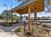Thumbnail 39 of 42 - A wooden shelter with a signboard is situated in a landscaped area.