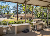 Thumbnail 14 of 14 - A covered outdoor kitchen area with a grill and sink.