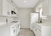 Thumbnail 4 of 13 - A white kitchen with a stove, oven, and refrigerator.