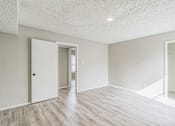 Thumbnail 9 of 13 - A room with a white door and a wooden floor.