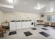 Thumbnail 10 of 12 - a laundry room with washer and dryers and tables and chairs