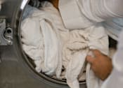 Thumbnail 4 of 4 - A person is taking out a white towel from a stainless steel washing machine.