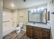 Thumbnail 4 of 8 - A bathroom with a white toilet, a wooden cabinet, and a large mirror.