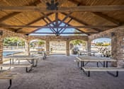 Thumbnail 8 of 8 - A covered outdoor seating area with tables and benches.