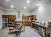 Thumbnail 6 of 8 - A kitchen with a table and chairs in the middle of the room.