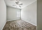 Thumbnail 3 of 8 - A room with a ceiling fan and wooden flooring.
