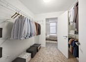 Thumbnail 11 of 13 - a walk in closet with clothes hanging on a rack and a door to a bedroom