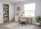Thumbnail 3 of 22 - A room with a desk, chair, and a potted plant.
