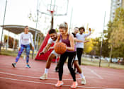 Thumbnail 3 of 4 - A group of people playing basketball on an outdoor court.