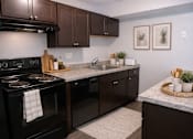Thumbnail 6 of 22 - A kitchen with black appliances and brown cabinets.