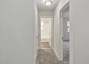 Thumbnail 11 of 13 - A long hallway with a carpeted floor and white walls.