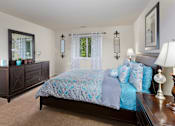 Thumbnail 19 of 32 - A bedroom with a bed, nightstand, and a dresser.