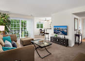 Thumbnail 17 of 32 - A living room with a couch, a coffee table, and a painting on the wall.