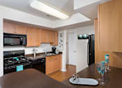Thumbnail 18 of 32 - A kitchen with a black refrigerator and a black stove.