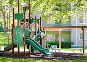 Thumbnail 26 of 32 - A playground with a green slide and a red structure.