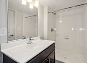 Thumbnail 7 of 30 - a bathroom with a sink and a shower and a mirror