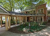 Thumbnail 18 of 24 - the front porch of a brick house with a sidewalk and trees
