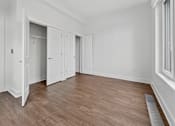 Thumbnail 9 of 20 - A room with white walls and wooden flooring with a door open to a hallway.