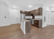 Thumbnail 6 of 20 - A kitchen with a white island and wooden floors.