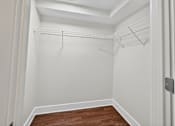 Thumbnail 13 of 20 - A white closet with a wooden floor and a white door.