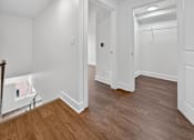 Thumbnail 12 of 20 - A hallway with wood floors and white walls.