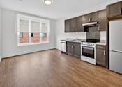 Thumbnail 17 of 20 - A kitchen with wooden floors and a window overlooking a brick building.