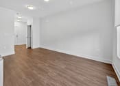 Thumbnail 16 of 20 - A room with wooden flooring and white walls.