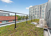 Thumbnail 20 of 20 - A rooftop with a metal railing and a green planted area.