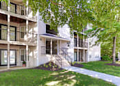 Thumbnail 9 of 13 - A white apartment building with a tree in front.