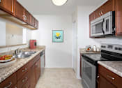 Thumbnail 3 of 13 - A kitchen with brown cabinets and a white fridge.