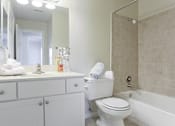 Thumbnail 7 of 13 - A white bathroom with a toilet, sink, and bathtub.