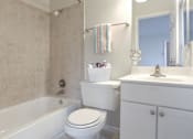 Thumbnail 6 of 13 - A white toilet sits next to a white sink in a bathroom.