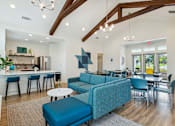 Thumbnail 9 of 19 - A modern living room with a blue sofa and a kitchen area in the background.