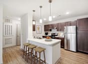 Thumbnail 3 of 19 - A kitchen with a white island and brown bar stools.